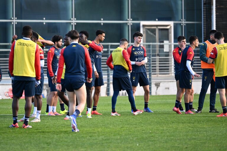 I giocatori del Genoa si confrontano sul campo durante una sessione di allenamento, con casacche rossoblù e gialle.