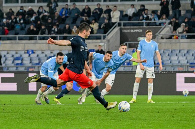 Ruslan Malinovskyi calcia il rigore del Genoa all’Olimpico di Roma mentre i giocatori della Lazio osservano, con il pallone pronto sul dischetto.