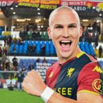 Leo Skiri Østigård sorride e alza il pugno con la maglia del Genoa CFC, davanti ai tifosi sugli spalti dello stadio durante la festa rossoblù.