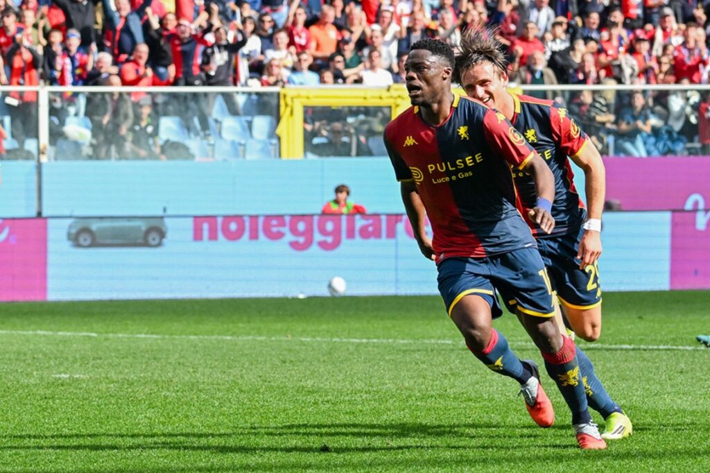 Durante Open Var, Ekuban del Genoa corre verso l'area davanti alla porta rossoblù, inseguito da un compagno, con gli spalti pieni.