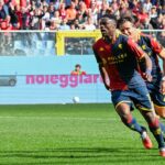 Durante Open Var, Ekuban del Genoa corre verso l'area davanti alla porta rossoblù, inseguito da un compagno, con gli spalti pieni.