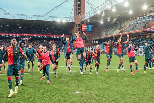 Il Genoa festeggia sul campo a fine partita, con i giocatori in maglia rossoblù che saltano e alzano le braccia nello stadio gremito.