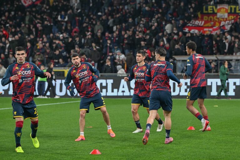 I giocatori del Genoa si riscaldano al Luigi Ferraris prima della sfida con il Napoli, tra maglie rossoblù e tifosi sugli spalti.