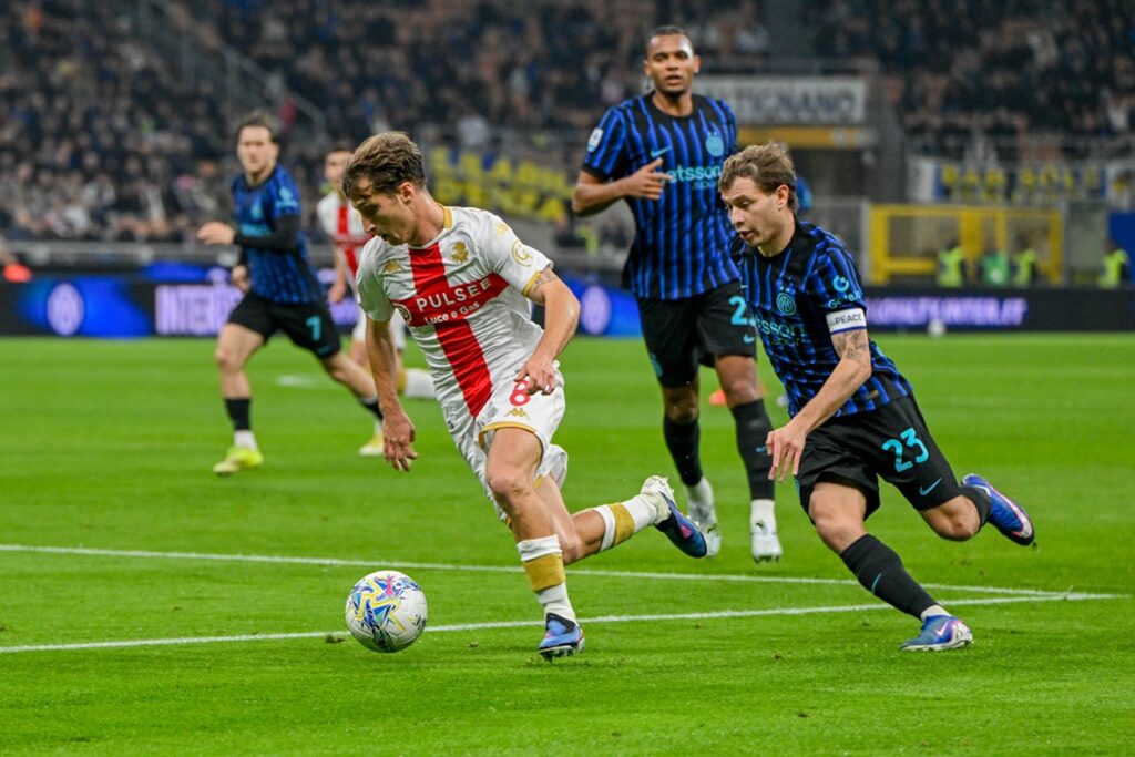 Al Meazza, un giocatore del Genoa in maglia bianca e rossa sfida un difensore dell’Inter in nerazzurro durante la gara di De Rossi finita 2-0.