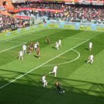 Norton-Cuffy del Genoa avanza palla al piede nell'area avversaria durante la sfida salvezza contro il Torino, con lo stadio gremito e la difesa schierata.