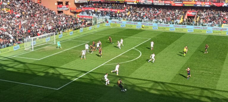 Norton-Cuffy del Genoa avanza palla al piede nell'area avversaria durante la sfida salvezza contro il Torino, con lo stadio gremito e la difesa schierata.