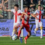 Nel match Cremonese-Genoa, Vitinha contende il pallone tra i difensori grigiorossi mentre il Genoa spinge nell'area avversaria.