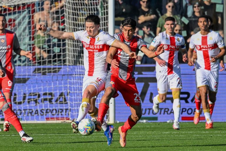 Nel match Cremonese-Genoa, Vitinha contende il pallone tra i difensori grigiorossi mentre il Genoa spinge nell'area avversaria.