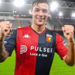 Dopo la vittoria del Paok a Salonicco, Alessandro Vogliacco sorride in maglia Genoa con i pugni alzati sotto le luci dello stadio.