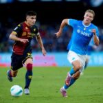 Nel Ferraris, un giocatore del Genoa in maglia rossoblù rincorre un avversario del Napoli in azzurro durante Genoa-Napoli, sfida intensa di campionato.