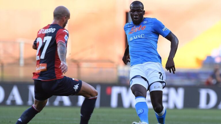 Un giocatore del Genoa in maglia rossoblù affronta un avversario del Napoli in azzurro durante la sfida Genoa-Napoli sul campo.
