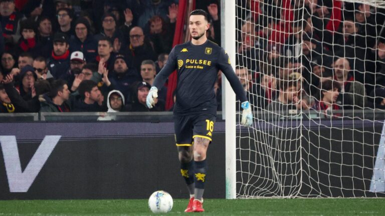 Bijlow, portiere del Genoa, in tenuta scura con numero 16 e guanti chiari, sul prato davanti alla porta mentre osserva il pallone, tra tifosi in tribuna.