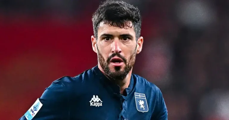 Aaron Martin, esterno sinistro del Genoa, in divisa blu scuro con stemma della squadra, viso concentrato durante una partita e controllo del pallone.