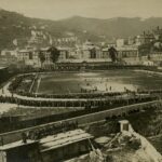 Veduta storica in stile sepia dello Stadio Ferraris e del Tempio di Marassi a Marassi, con il campo e le tribune gremite di pubblico.