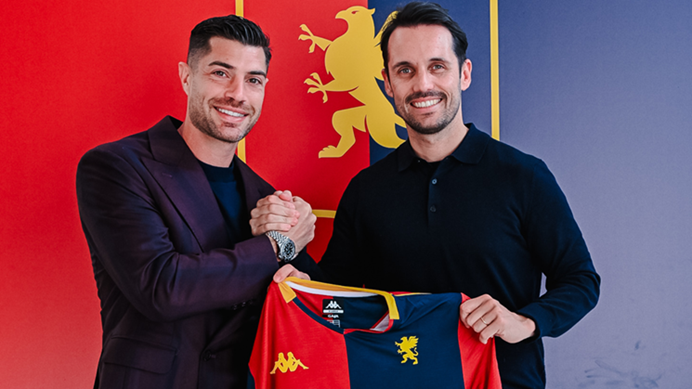 Stefano Sabelli in posa con la maglia rossoblù del Genoa, con sfondo rosso e blu: abbraccio e sorriso durante il rinnovo fino al 2028