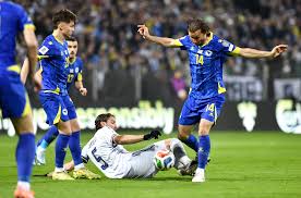 Italia contro Bosnia Erzegovina: giocatori in maglie blu si contengono sul campo verde, pubblico sullo sfondo, tensione e contesa sportiva tra le squadre.