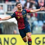 Malinovskyi del Genoa in maglia rossa-blu, braccia aperte in gesto di esultanza durante Genoa Sassuolo 2-1, pubblico sullo sfondo.
