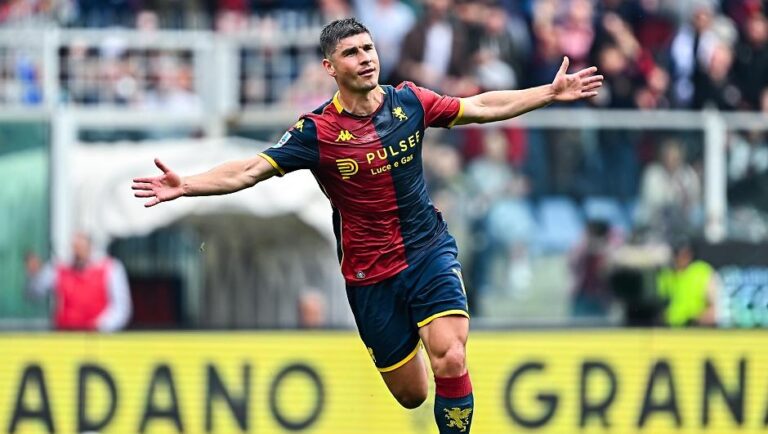 Malinovskyi del Genoa in maglia rossa-blu, braccia aperte in gesto di esultanza durante Genoa Sassuolo 2-1, pubblico sullo sfondo.