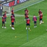 Giocatori in maglia rosso-nero schierati sul prato verde allo stadio New Balance Arena di Bergamo, Atalanta e Genoa in formazioni ufficiali.