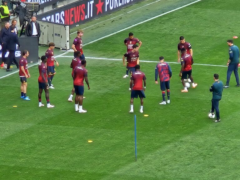 Giocatori in maglia rosso-nero schierati sul prato verde allo stadio New Balance Arena di Bergamo, Atalanta e Genoa in formazioni ufficiali.