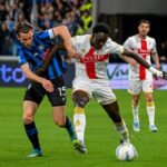 Contrasto in Atalanta-Genoa con Ekhator in maglia blu-nero, avversario in bianco-rosso, palla in gioco: intensità e grinta da partita combattuta.