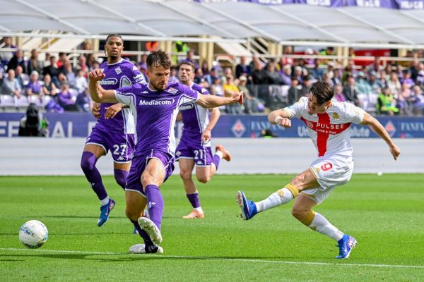 Contrasto in Fiorentina–Genoa: giocatori in maglia viola e bianca, palla sull’erba al Franchi, pagelle dopo una gara avara di occasioni e Massimi.