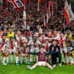 Genoa in festa a Bergamo: giocatori e tifosi con bandiere rosso-blu, sul prato dopo la salvezza in Serie A