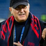 Il presidente Sucu, con berretto nero e sciarpa del Genoa, sorride durante il saluto alla squadra prima del ritiro.
