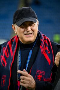 Il presidente Sucu, con berretto nero e sciarpa del Genoa, sorride durante il saluto alla squadra prima del ritiro.